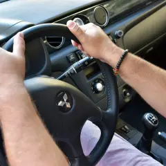 Ręce na kierownicy Mitsubishi. Słychać niepokojące trzeszczenie przy skręcaniu kierownicą na postoju.