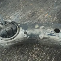 Uszkodzony, brudny wahacz z urwanym sworzniem. Narzędzie włożone w miejsce mocowania.