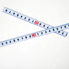 Dwie miarki zwinięte na białym tle. Jedna pokazuje 20, druga 30. Kluczowe dla określenia szerokość felgi a opona.