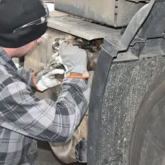Mechanik w rękawiczkach pracuje przy samochodzie ciężarowym, próbując dowiedzieć się, jak wyczyścić dpf domowym sposobem.