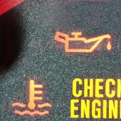 Pomarańczowa kontrolka oleju świeci się obok ikony termometru i napisu "CHECK ENGINE".