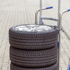 Stos czterech opon samochodowych na wózku. Zastanawiasz się, ile waży opona? Ten zestaw jest gotowy do transportu.