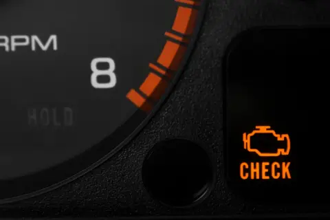 Pomarańczowy symbol "CHECK ENGINE" świeci się, sygnalizując migający check engine i nierówną pracę silnika. Obok widać fragment obrotomierza.