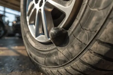 Widoczne wybrzuszenie na oponie, świadczące o jej uszkodzeniu. Pęknięcia na gumie pogarszają sytuację.