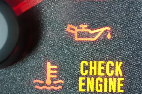 Pomarańczowa kontrolka oleju świeci się obok ikony termometru i napisu "CHECK ENGINE".
