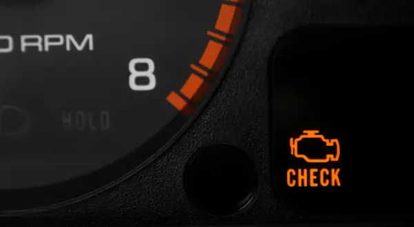 Pomarańczowy symbol "CHECK ENGINE" świeci się, sygnalizując migający check engine i nierówną pracę silnika. Obok widać fragment obrotomierza.