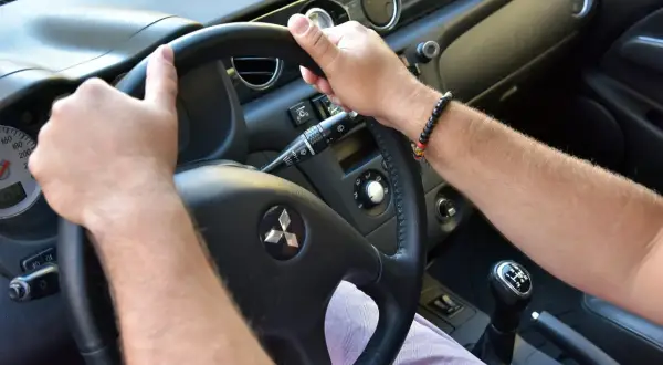Ręce na kierownicy Mitsubishi. Słychać niepokojące trzeszczenie przy skręcaniu kierownicą na postoju.