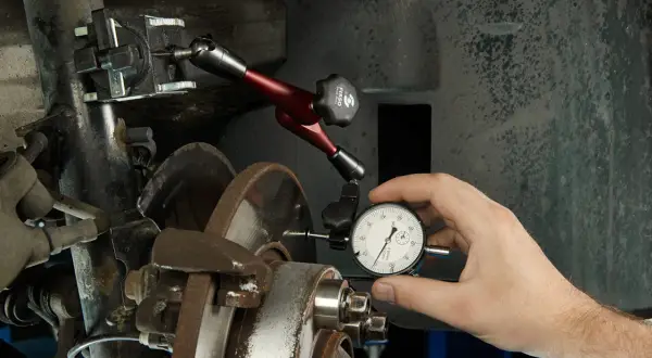 Mechanik mierzy bicie tarczy hamulcowej, aby zapobiec drganiom przy hamowaniu z dużej prędkości.