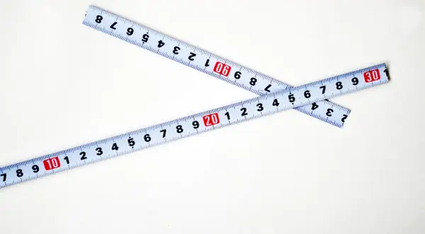 Dwie miarki zwinięte na białym tle. Jedna pokazuje 20, druga 30. Kluczowe dla określenia szerokość felgi a opona.