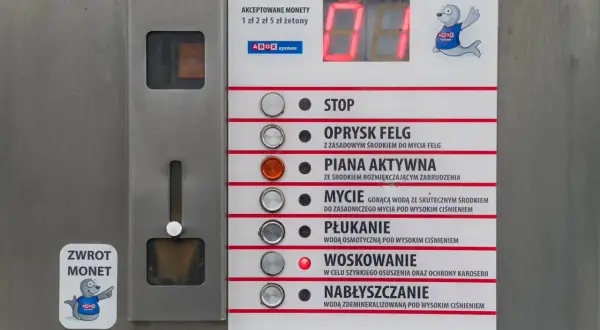 Panel myjni samochodowej z przyciskami: STOP, OPRYSK FELG, PIANA AKTYWNA, MYCIE, PŁUKANIE, WOSKOWANIE, NABŁYSZCZANIE. Instrukcja jak myć samochód na myjni.