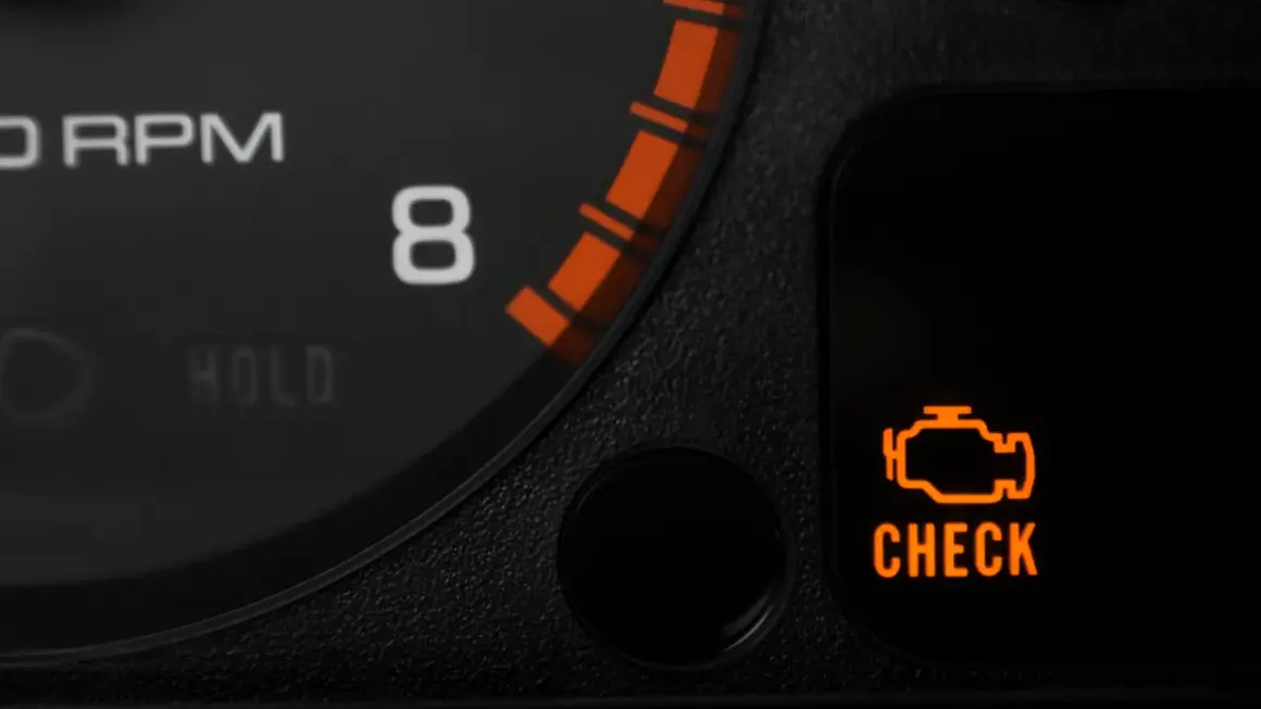 Pomarańczowy symbol "CHECK ENGINE" świeci się, sygnalizując migający check engine i nierówną pracę silnika. Obok widać fragment obrotomierza.