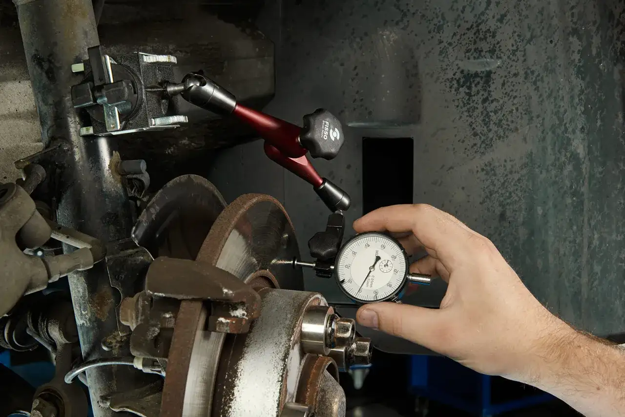 Mechanik mierzy bicie tarczy hamulcowej, by wyeliminować drgania przy hamowaniu z dużej prędkości.