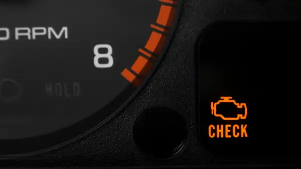 Pomarańczowy symbol "CHECK ENGINE" świeci się, sygnalizując migający check engine i nierówną pracę silnika. Obok widać fragment obrotomierza.