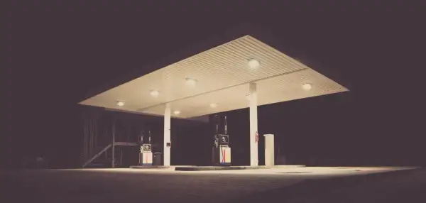 Nocna stacja benzynowa. Dwie dystrybutory paliwa czekają na kierowców, którzy zastanawiają się, czy wybrać benzynę 95 czy 98.
