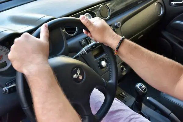 Ręce na kierownicy Mitsubishi. Słychać niepokojące trzeszczenie przy skręcaniu kierownicą na postoju.