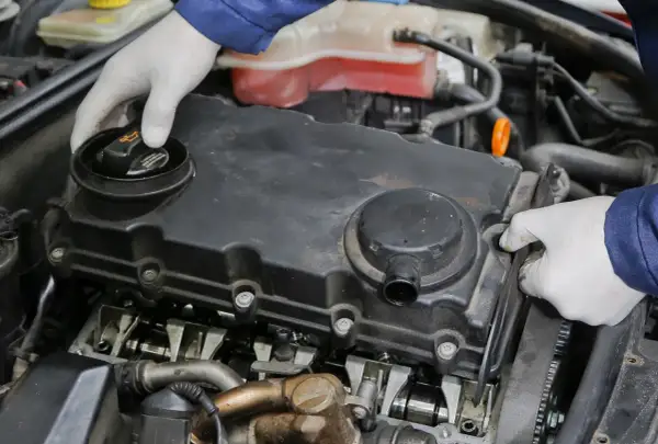 Mechanik w białych rękawiczkach sprawdza silnik. Może to być związane z nieszczelna odma objawy, które wymagają uwagi.