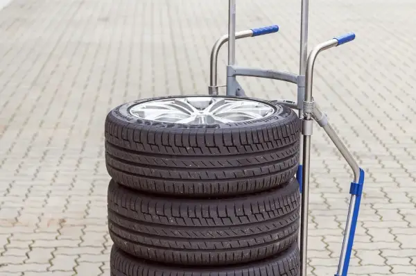 Stos czterech opon samochodowych na wózku. Zastanawiasz się, ile waży opona? Ten zestaw jest gotowy do transportu.